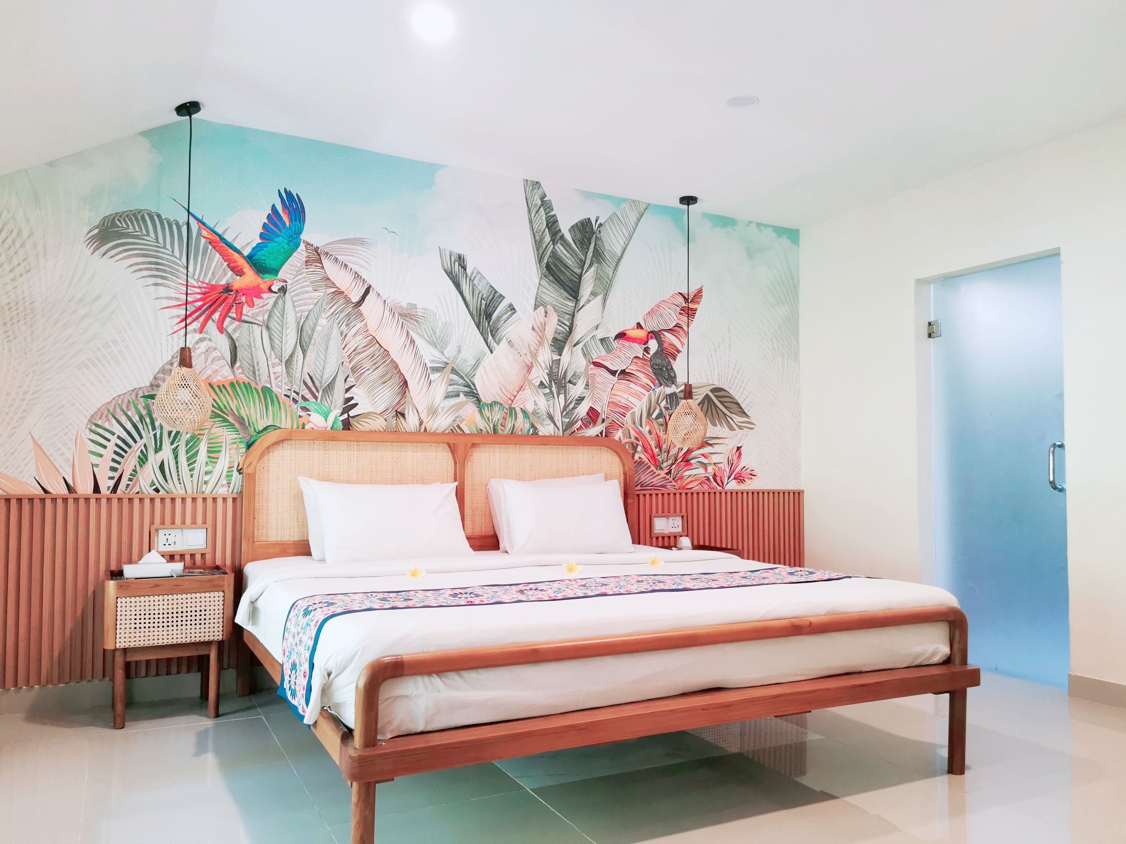 A bedroom with a bed, nightstands, a wall mural, and a door.