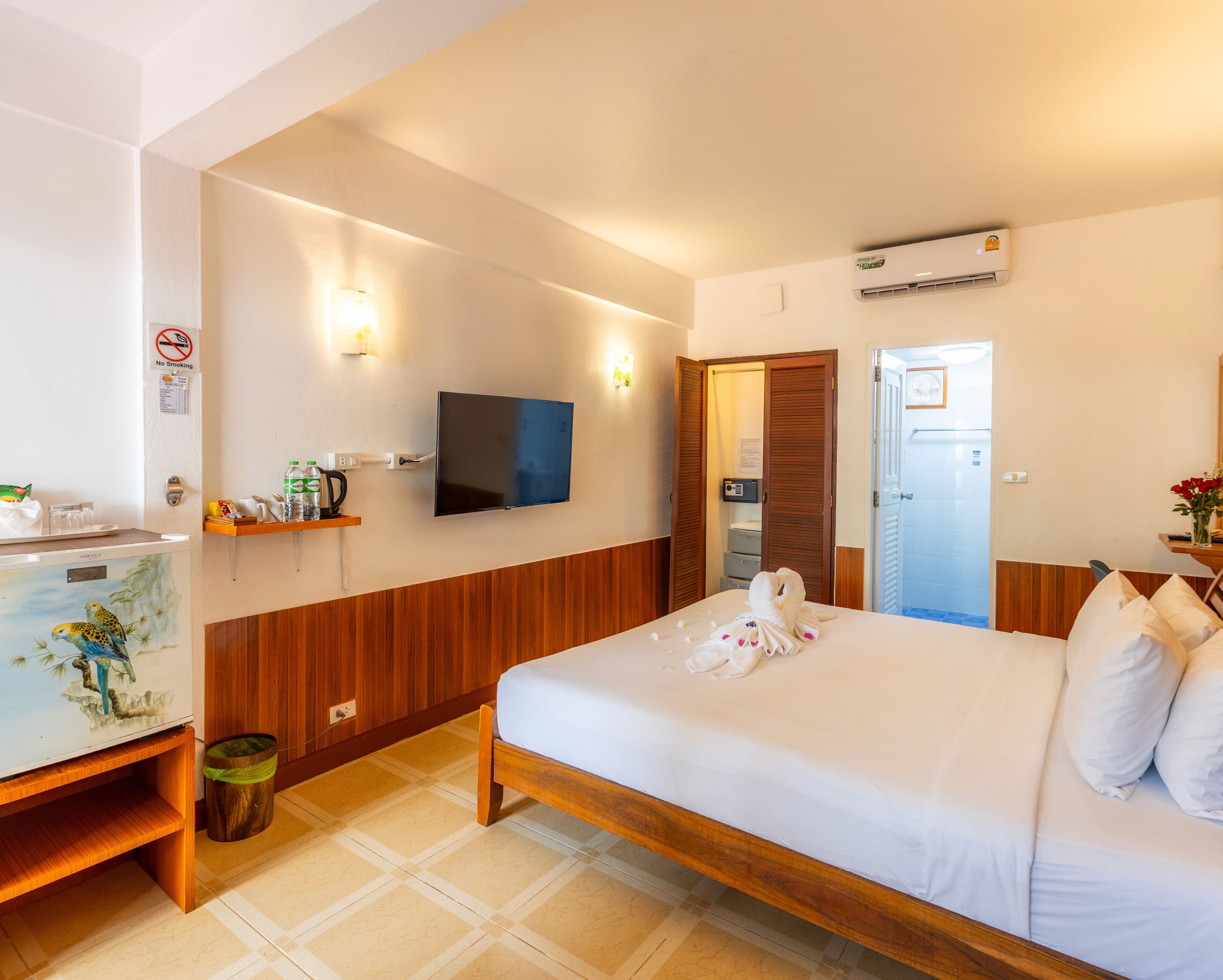 Une chambre d’hôtel équipée d’un lit, d’un téléviseur fixé au mur, d’un petit bureau avec un téléphone et d’une poubelle.