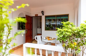 Una habitación con una mesa redonda, una silla, un ventanal con vistas a edificios y una puerta.