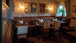 A restaurant with a high-backed booth seating area, wooden tables, and chairs. - Crown Inn (Chippenham)