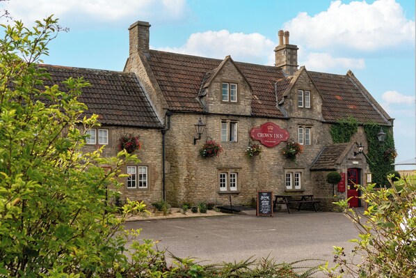 A traditional stone building with a sign for 'The Crown Inn' pub and rooms. - Crown Inn (Chippenham)