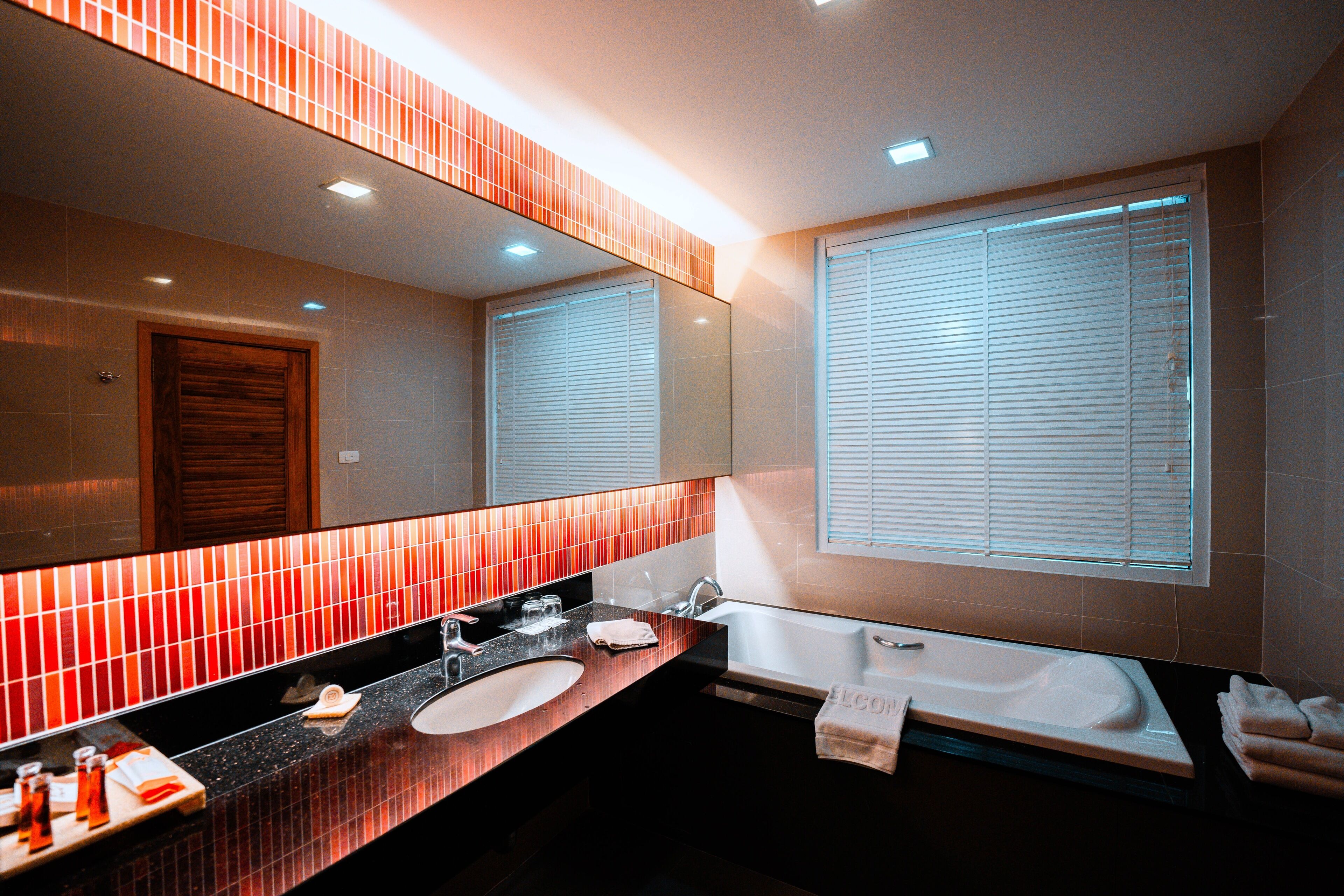 Une salle de bain moderne avec un grand miroir, une baignoire et un meuble-lavabo.
