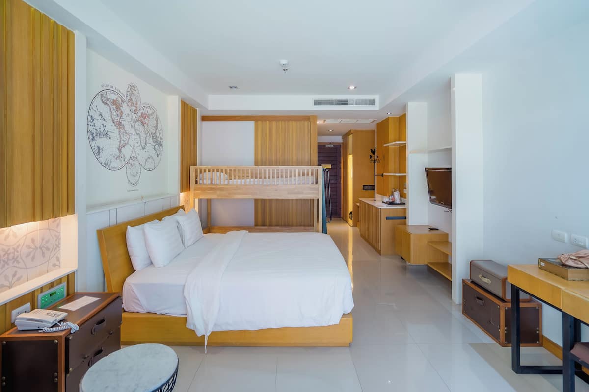 A modern hotel room with a bunk bed, a desk with a computer, a wardrobe, and a map on the wall.