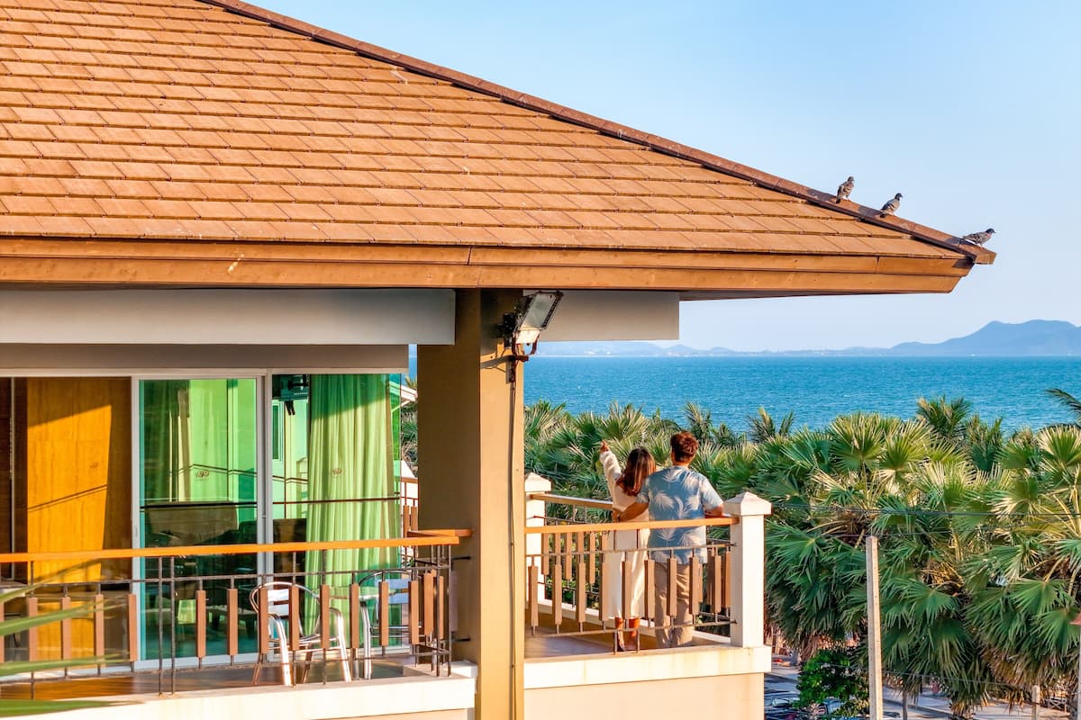 A balcony with a view of the sea, a tiled roof, and a railing.
