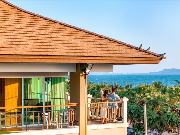 A balcony with a view of the sea, a tiled roof, and a railing. - Welcome World Beachfront Resort (Pattaya)
