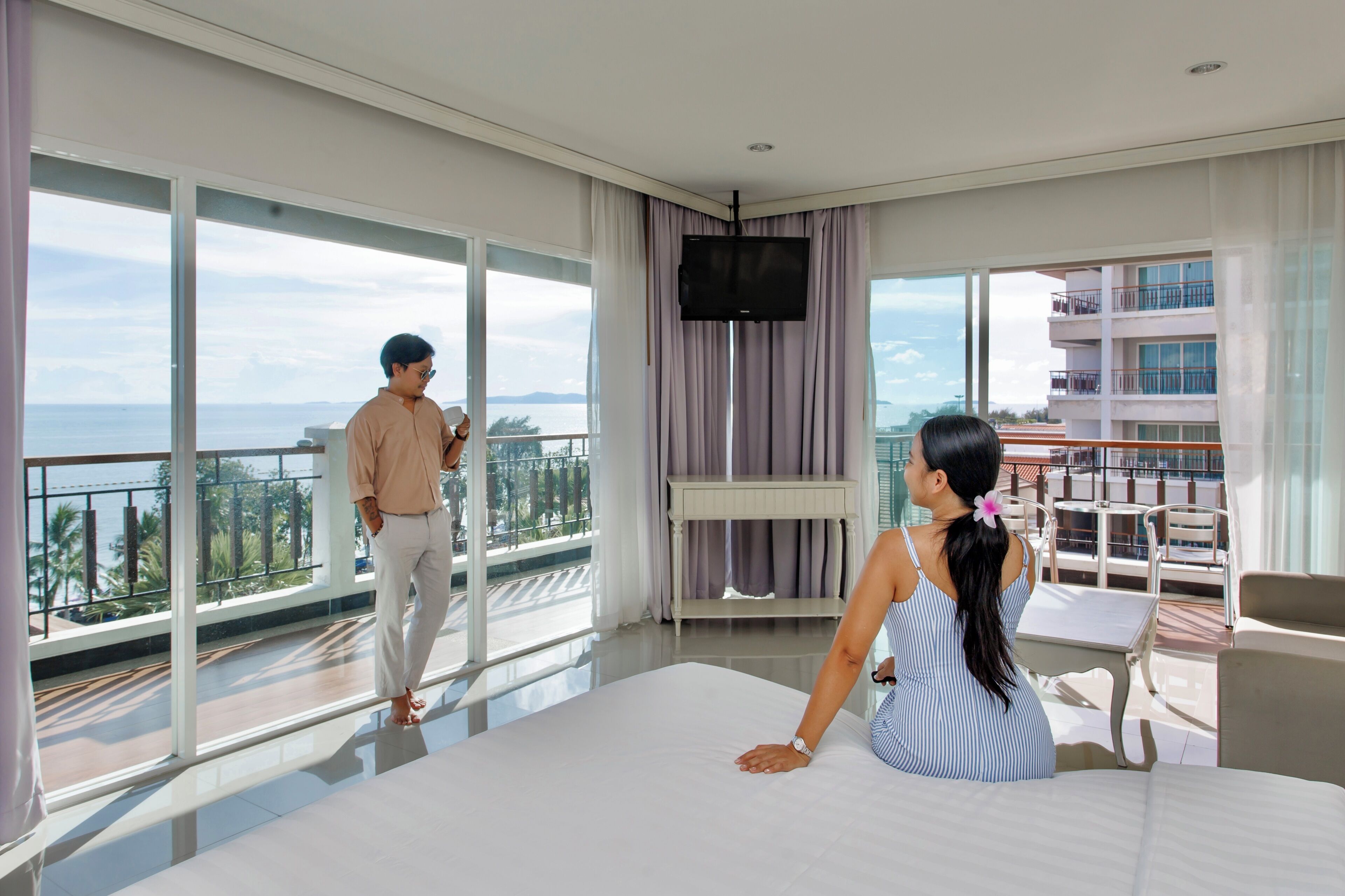 Une chambre d’hôtel avec balcon, télévision et vue sur la mer.