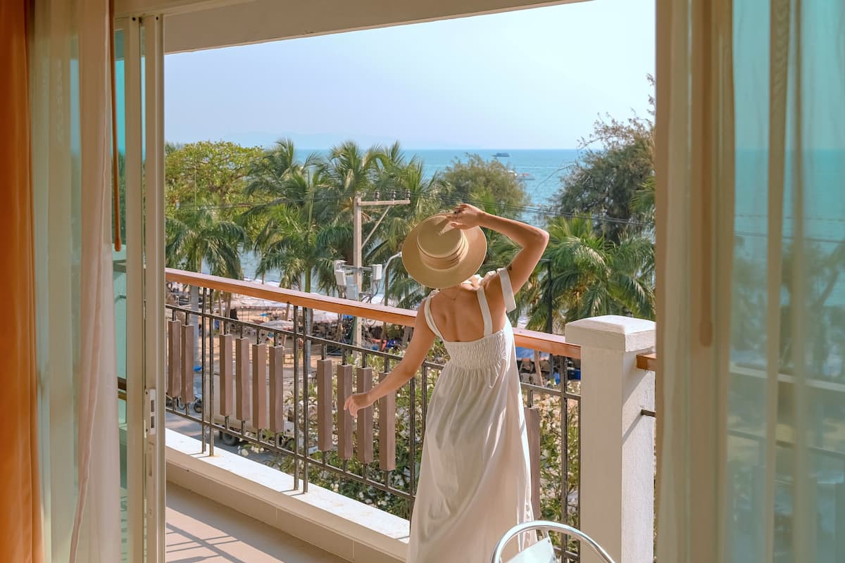 A balcony with a view of the ocean and palm trees.