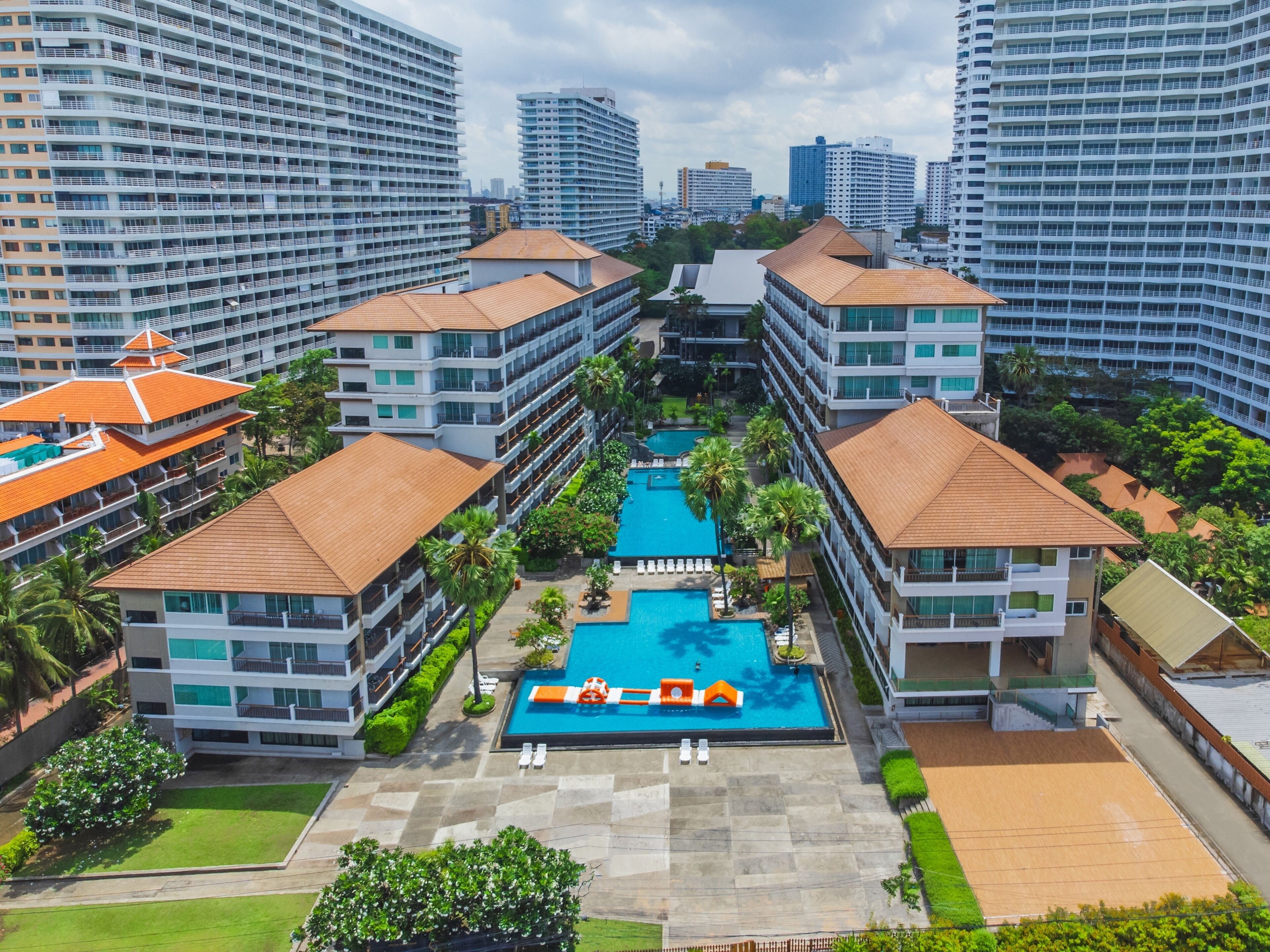 Un hôtel de grande hauteur doté de nombreux balcons, d’une piscine centrale et entouré de verdure.