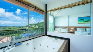 Une salle de bain moderne dotée d’une grande baignoire, d’un balcon offrant une vue sur le paysage et d’un grand miroir qui reflète la pièce.