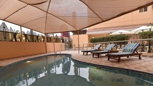 A pool area with lounge chairs and a covered seating area. - Boudl Al Maidan (Hafr Al Batin)