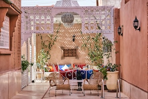 An outdoor seating area with wicker chairs, a table, and potted plants. - Riad Ouarzazate (Ouarzazate)