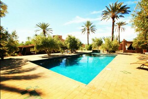 Una piscina al aire libre, sillones reclinables de piscina