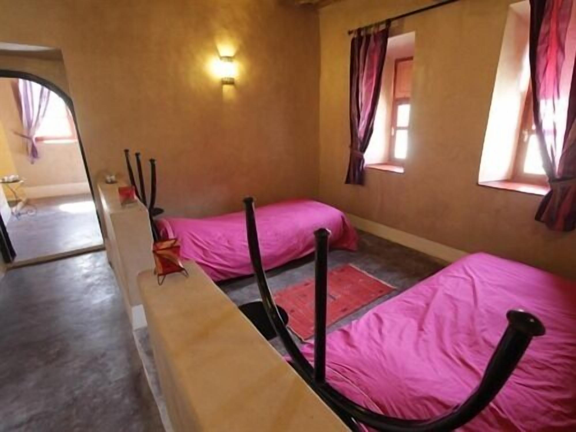 Een kamer met twee bedden, een spiegel en een raam met gordijnen.