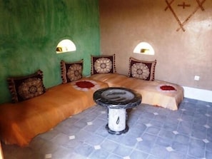A room with a bed, a small round table, and two wall-mounted lights.