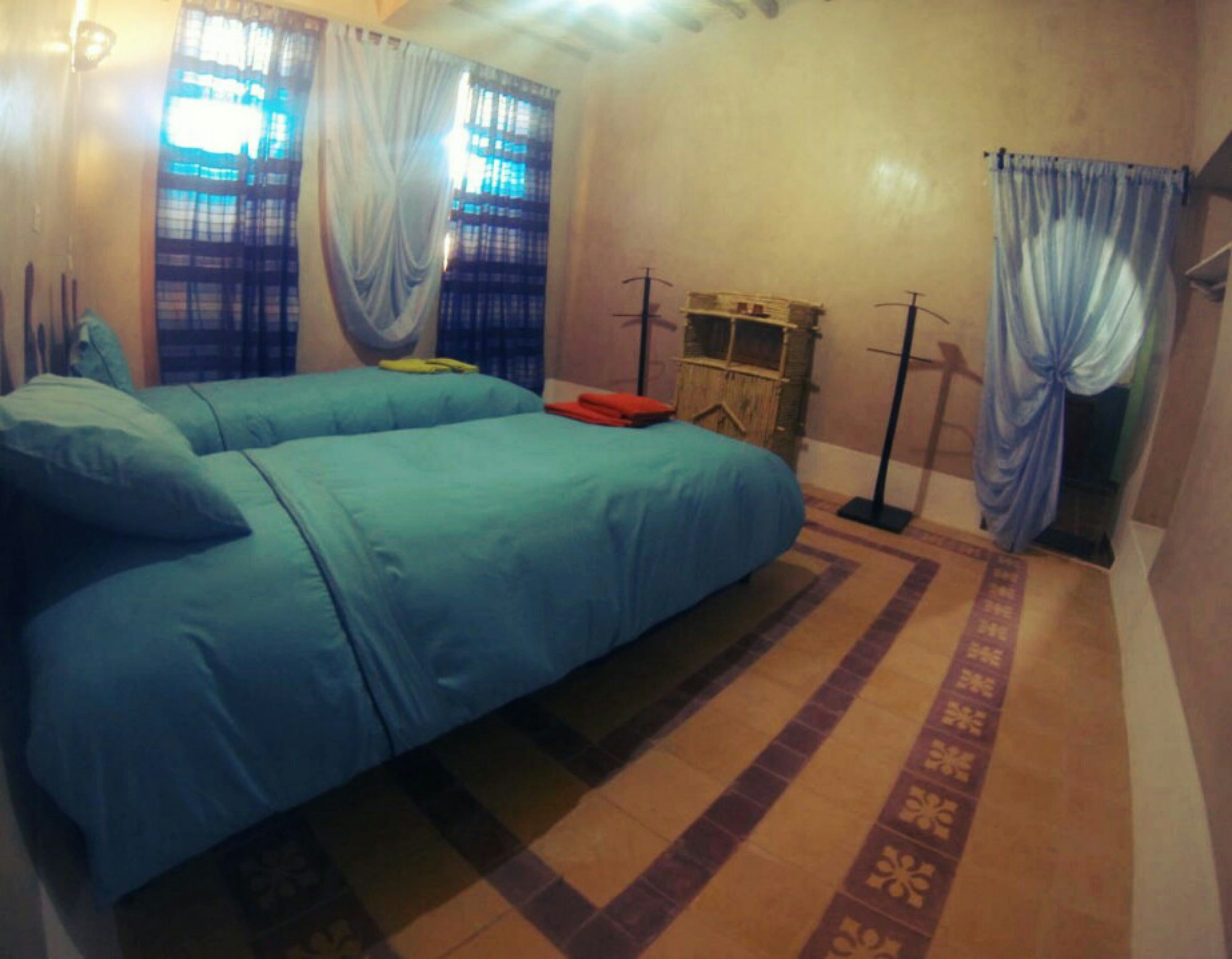 Une chambre avec deux lits, une petite table et un ventilateur.