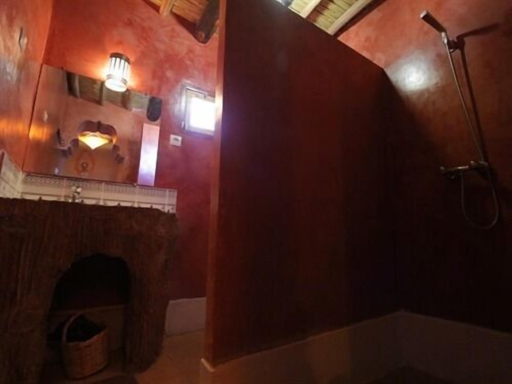 Ein Badezimmer mit einem Holzbadezimmerhocker, einer Dusche und einem kleinen Fenster.