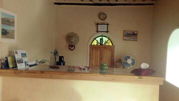 A kitchen area with a wooden counter, a clock, a hat, and a fan.