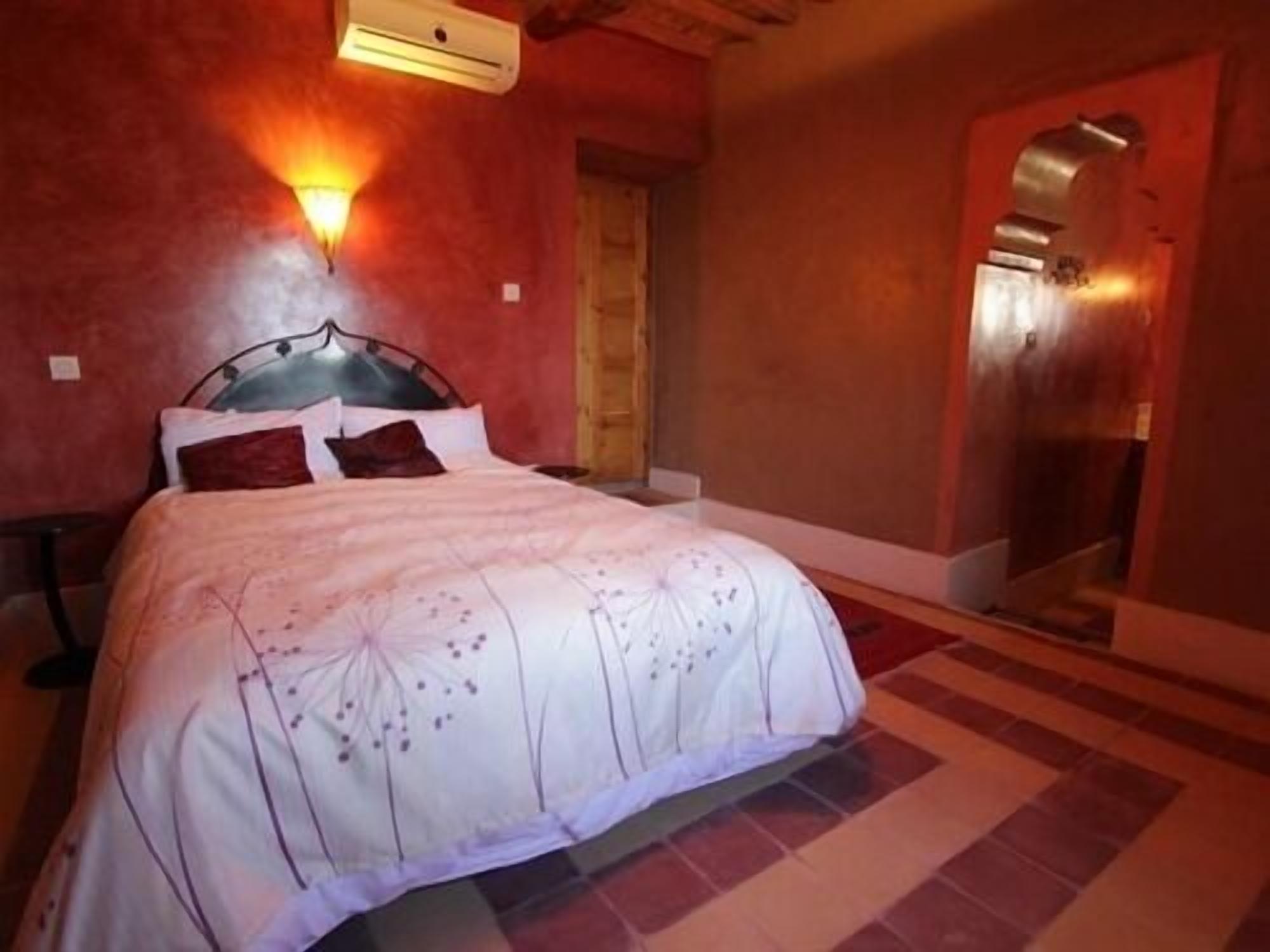 A bedroom with a bed, a wall-mounted air conditioner, and a door.