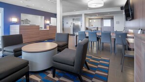 A modern hotel lobby with a reception desk, seating area, and a dining space. - Microtel Inn & Suites By Wyndham Moorhead Fargo Area (Moorhead)