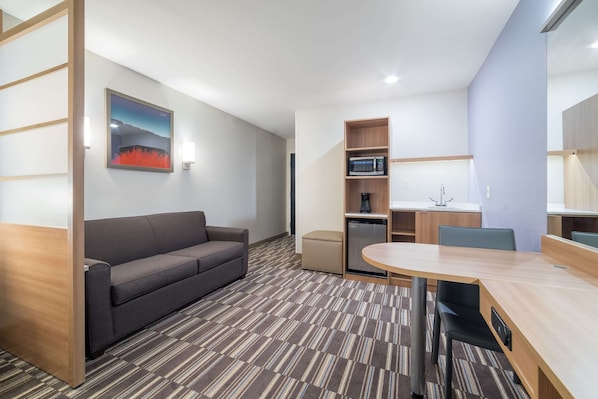 Une chambre d’hôtel moderne équipée d’un canapé, d’une table à manger, d’un four à micro-ondes et d’une petite kitchenette.