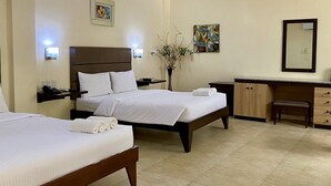 Een hotelkamer met twee bedden, een bureau, een stoel, een vaas met takken en kunst aan de muren.