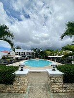 Una piscina al aire libre, sombrillas, sillones reclinables de piscina