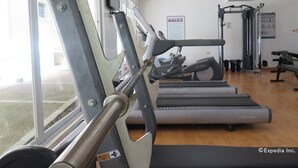 Een sportschool met loopbanden, krachttoestellen en een bord met regels.
