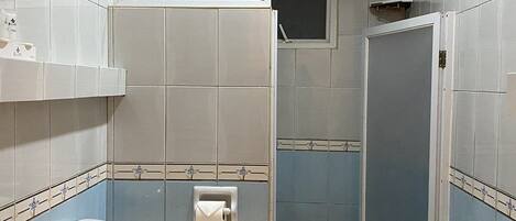 Een kleine badkamer met toilet, wastafel en douche.