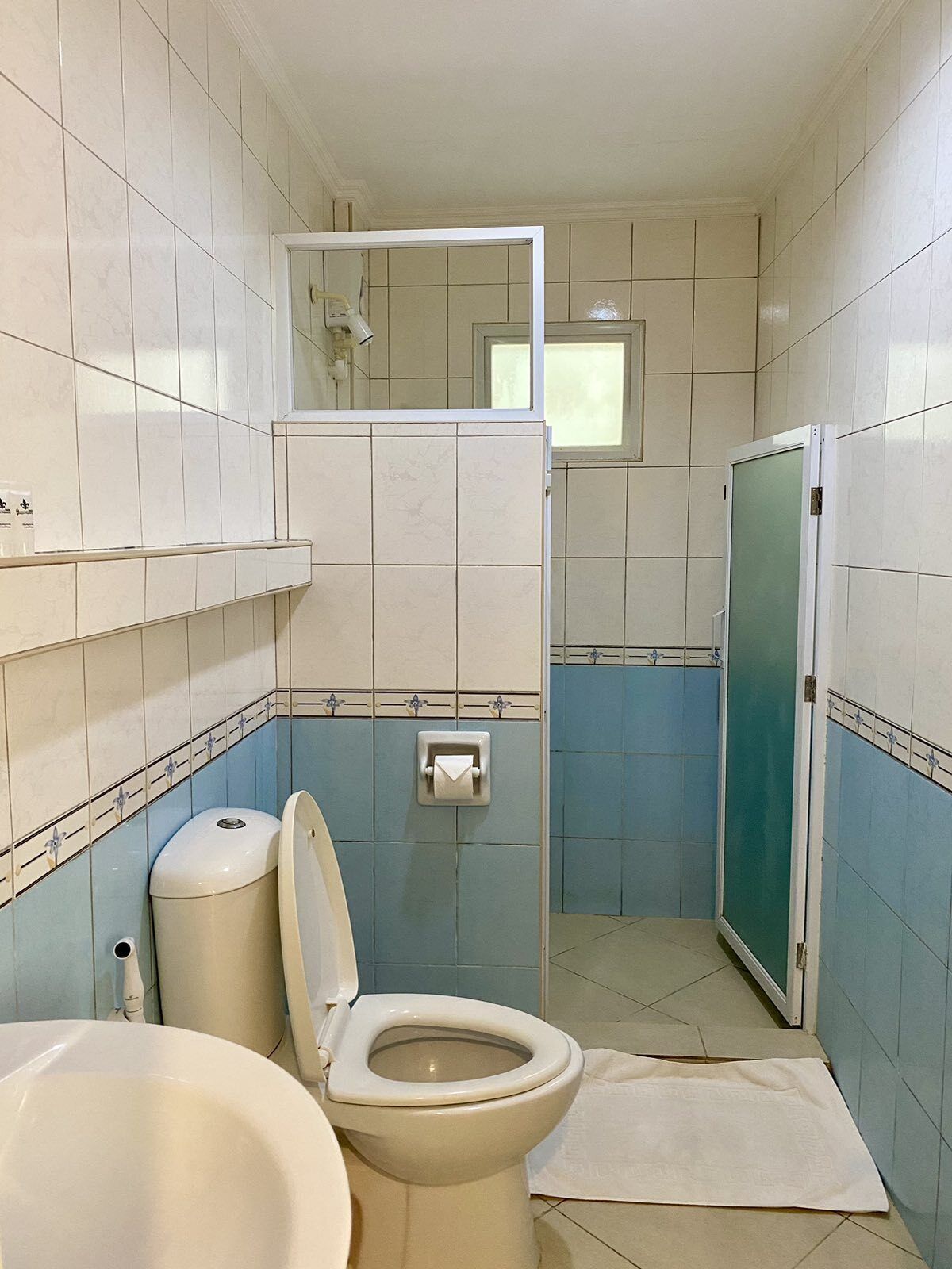 A bathroom with a toilet, sink, and shower area.
