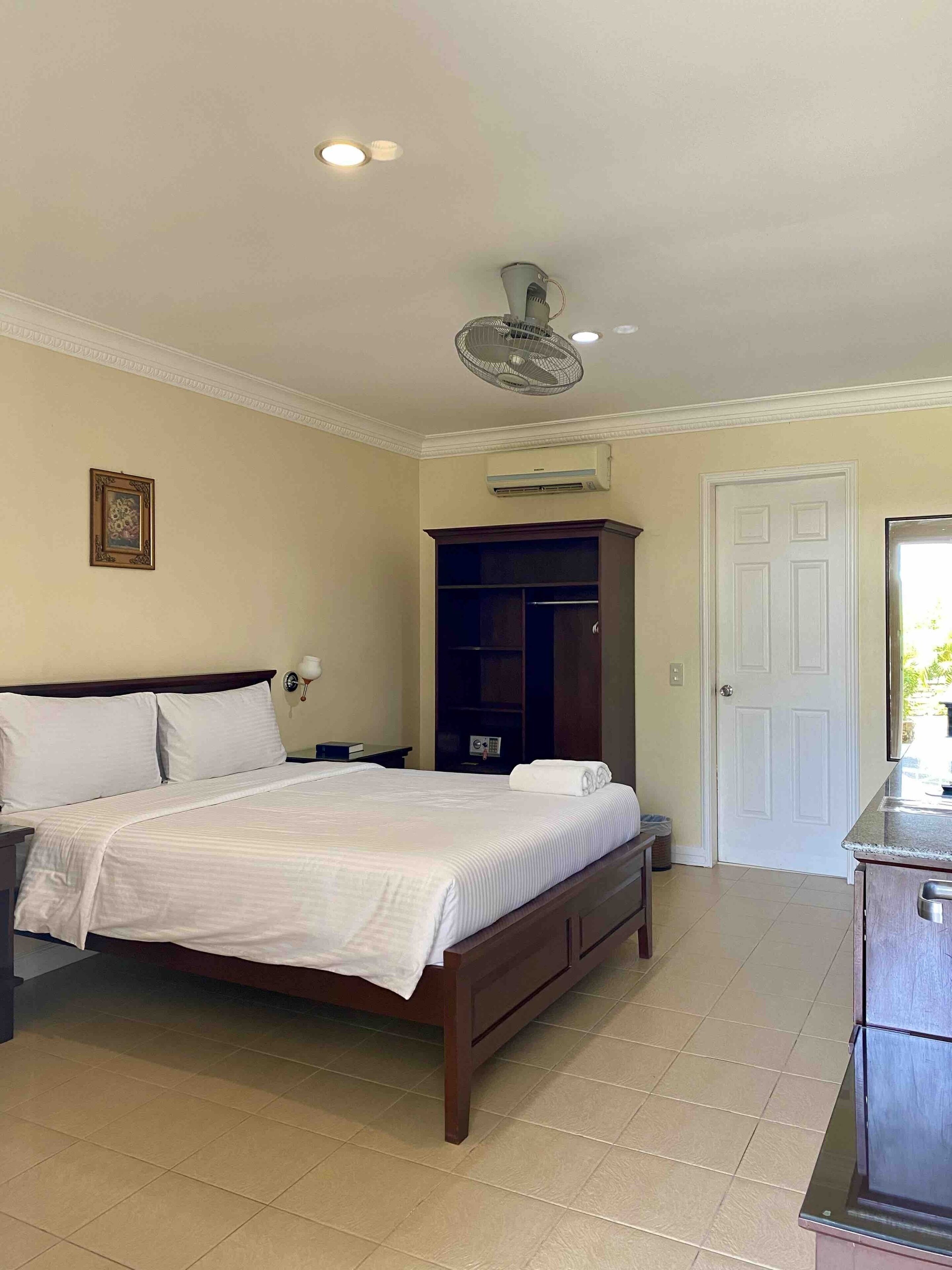 Un dormitorio con cama, armario, ventilador de techo y aire acondicionado.