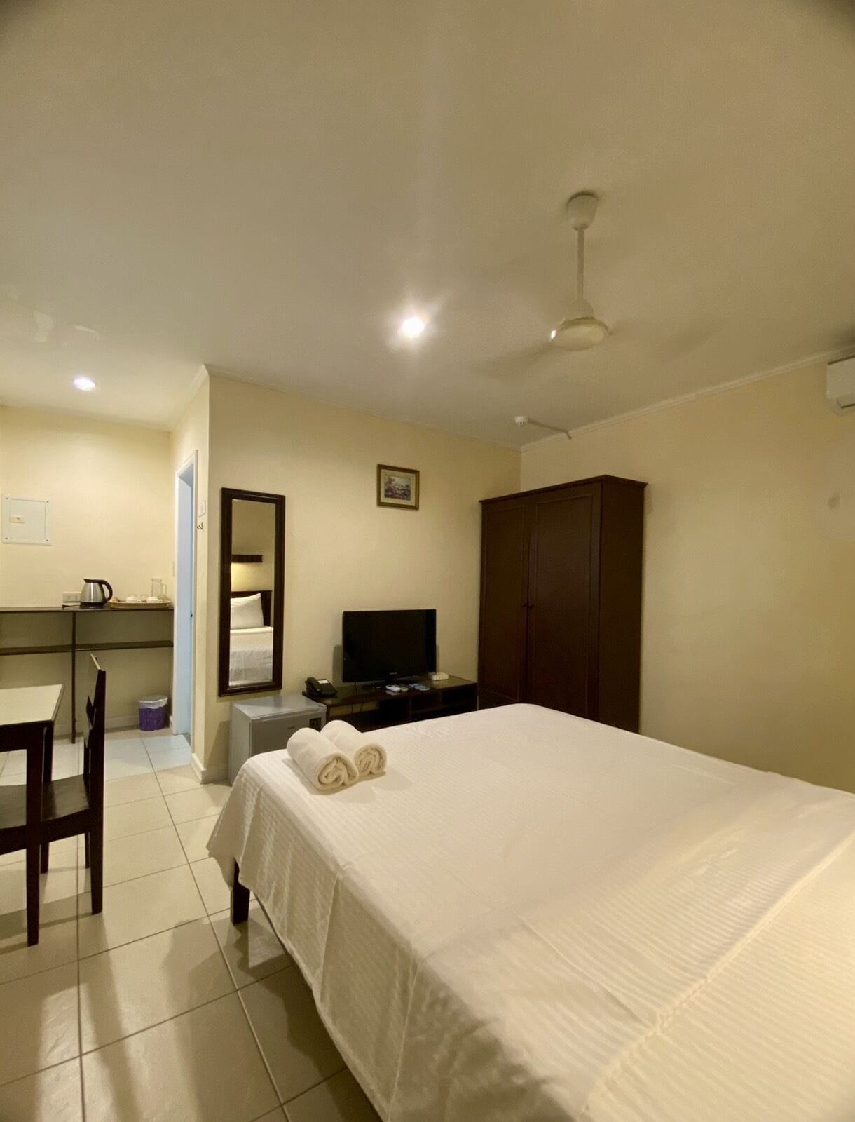 Una habitación de hotel con una cama, un escritorio con computadora, televisor y armario.