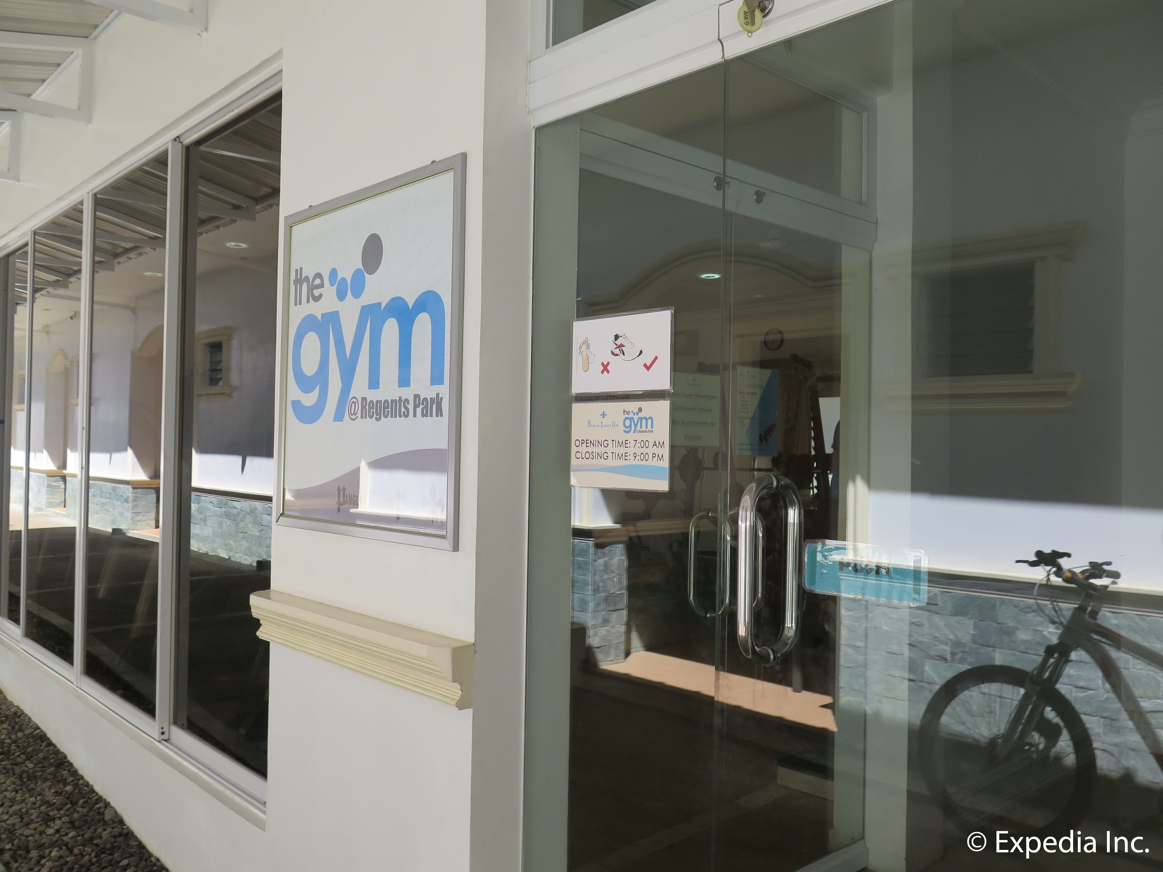 A gym entrance with a sign reading "The Gym @ Regents Park" and a posted schedule.