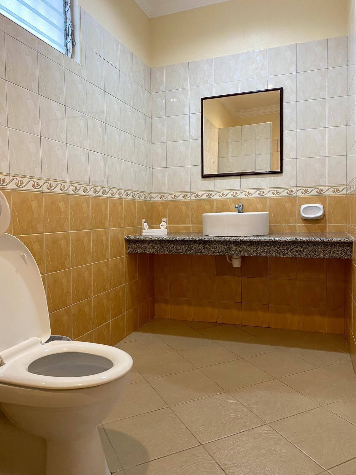 Un baño con inodoro, lavabo, espejo y secador de manos.