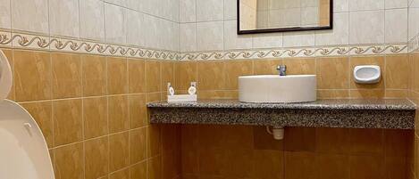 Un baño con inodoro, lavabo, espejo y secador de manos.