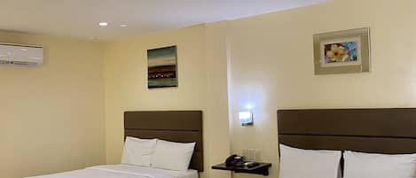 A hotel room with two beds, a nightstand, an air conditioning unit, and a wall-mounted picture.