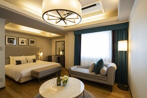 Una habitación de hotel con una cama grande, un sofá, una mesa de centro redonda y un candelabro.