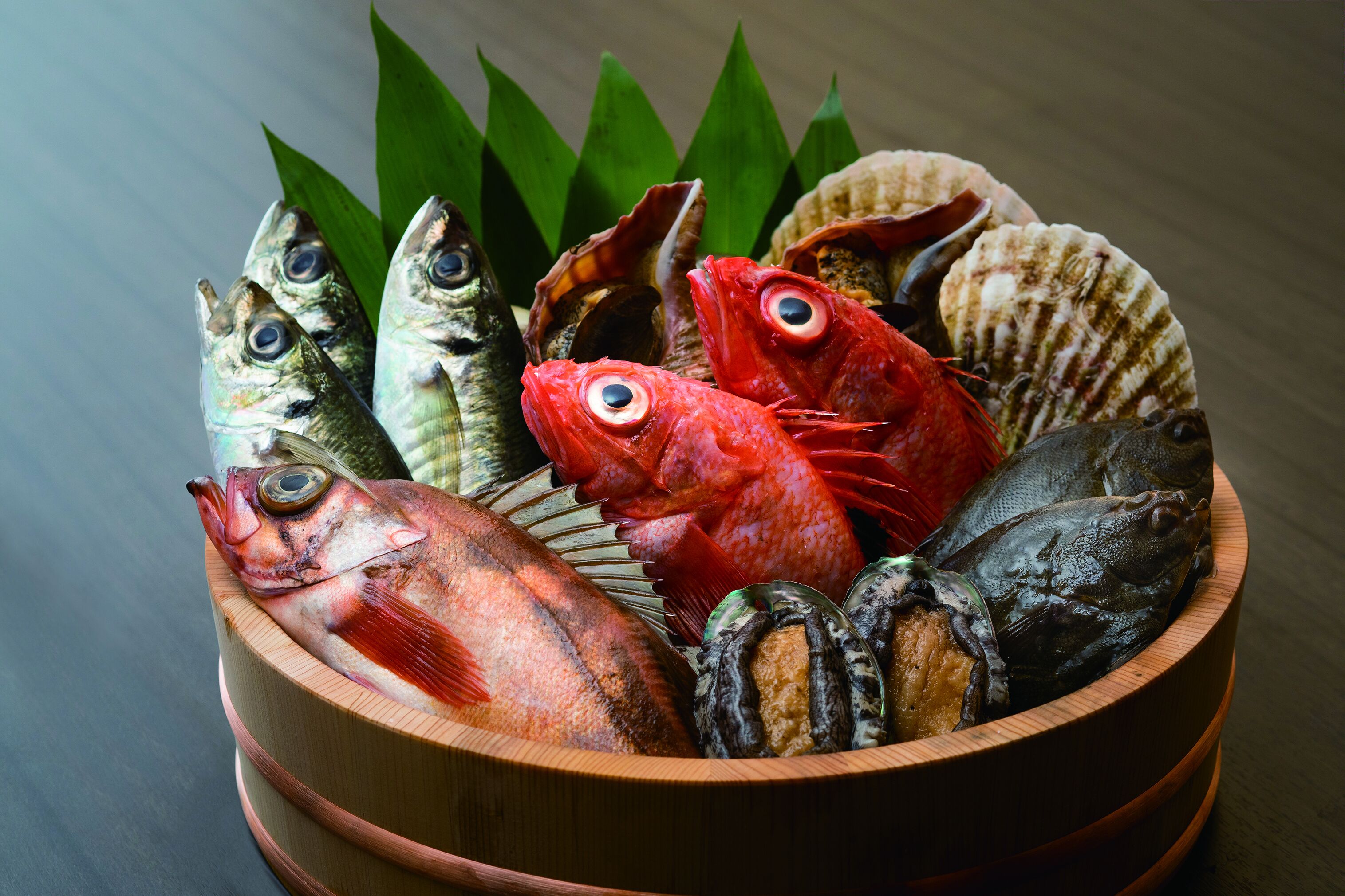 Un bol en bois contenant divers poissons et coquillages.