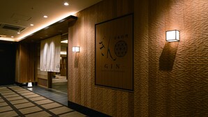 Un pasillo con pared texturizada, un letrero de madera con caracteres japoneses y dos luces fijadas a la pared.