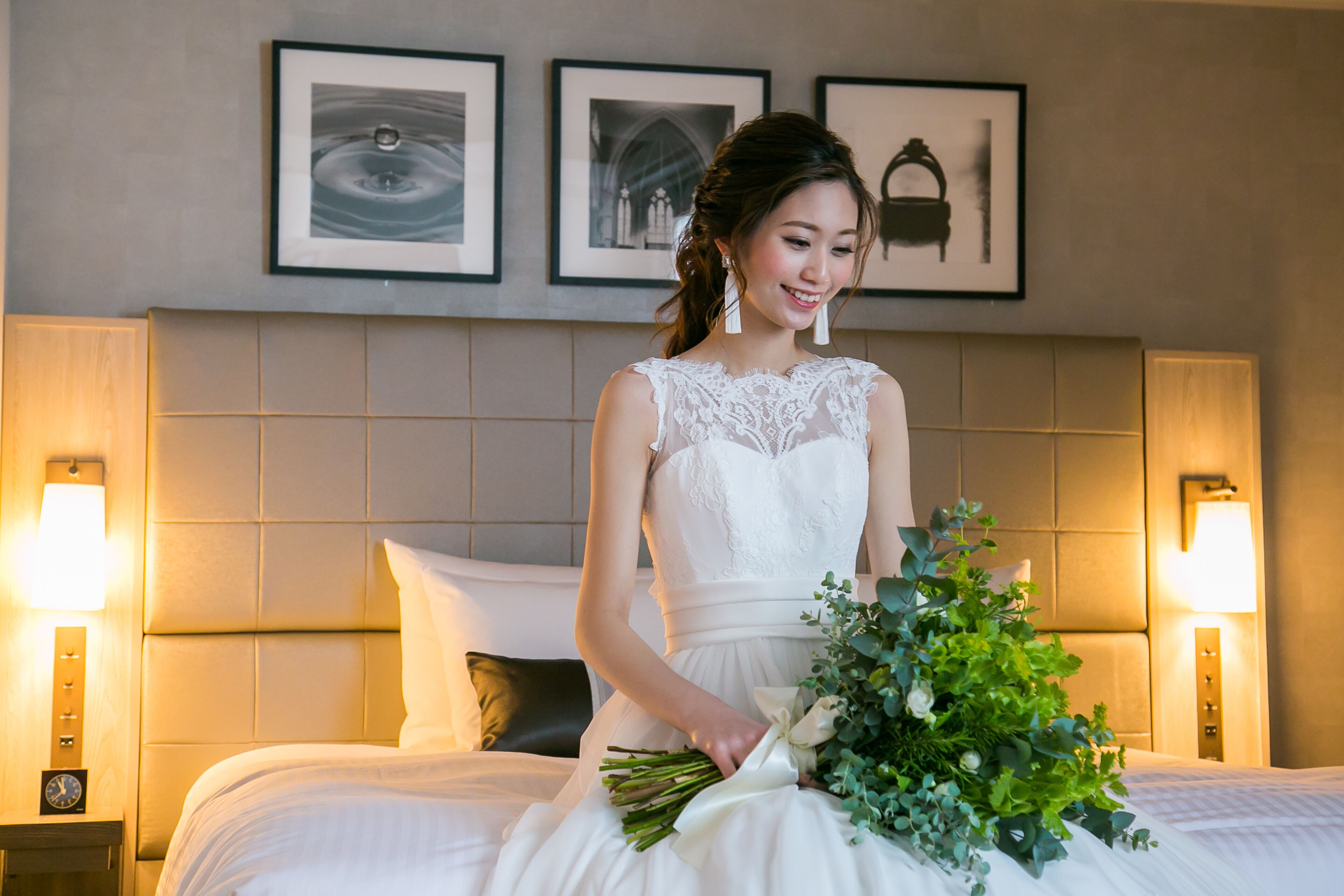 Une suite nuptiale comprenant un grand lit, une tête de lit, des tableaux encadrés au mur et des lampes de chevet.
