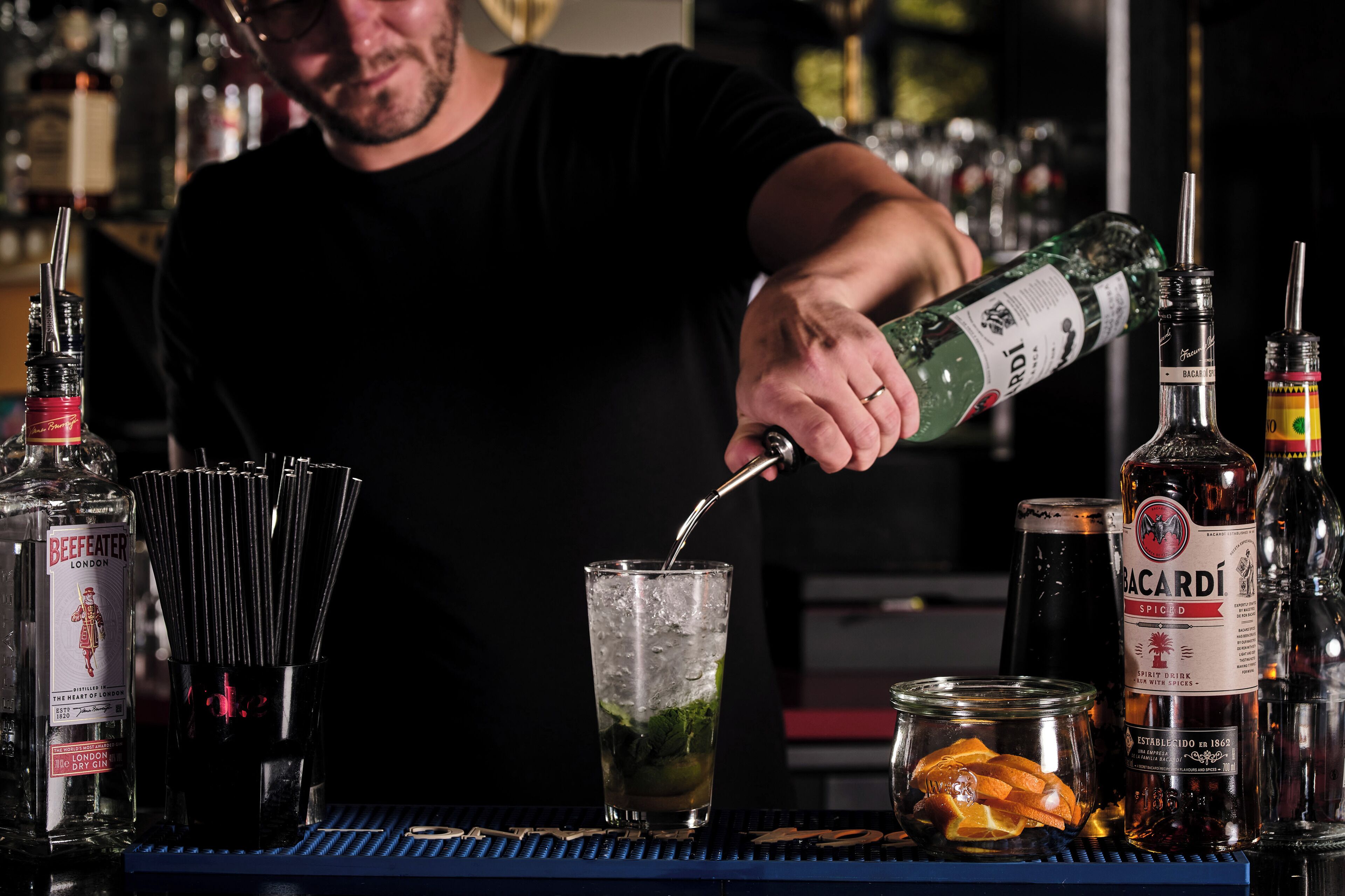 Ein Barkeeper gießt ein Getränk in ein Glas mit Eis.