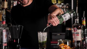 Ein Barkeeper gießt ein Getränk in ein Glas mit Eis.