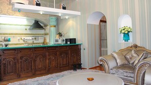 A spacious living room with a large, round coffee table, a sofa, and a kitchen area with a wooden cabinet and a microwave. - Odessa City Center Apartments (Odesa)