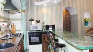 A kitchen with a marble countertop, stainless steel appliances, and a bar area with stools. - Odessa City Center Apartments (Odesa)