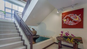 A staircase leading to a balcony with a view, a decorative wall piece, and a wooden bench with flowers. - Le Viengping (Chiang Mai)