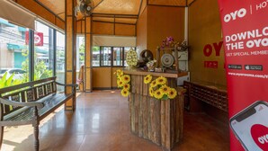A reception area with a wooden counter, a bench, and a large red sign advertising a mobile app. - Le Viengping (Chiang Mai)