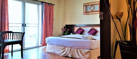Una habitación de hotel con cama, una silla, ventana con cortinas y aire acondicionado de pared.