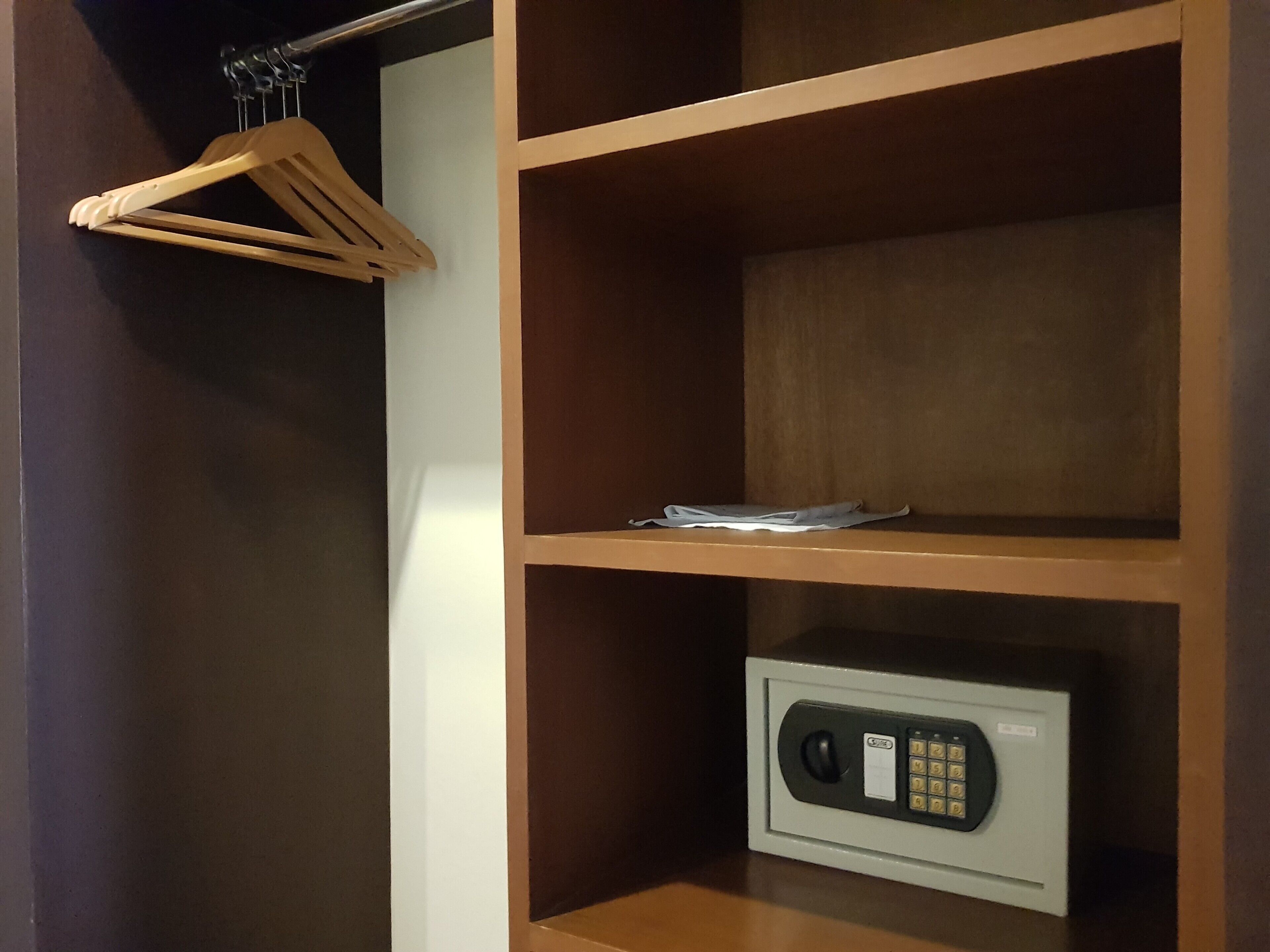 Una habitación con un armario de madera, una caja fuerte y un juego de perchas de madera.