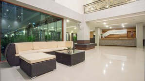 A modern lobby with a reception desk, a sofa, and a coffee table. - Pangviman Place Resotel (Chiang Mai)