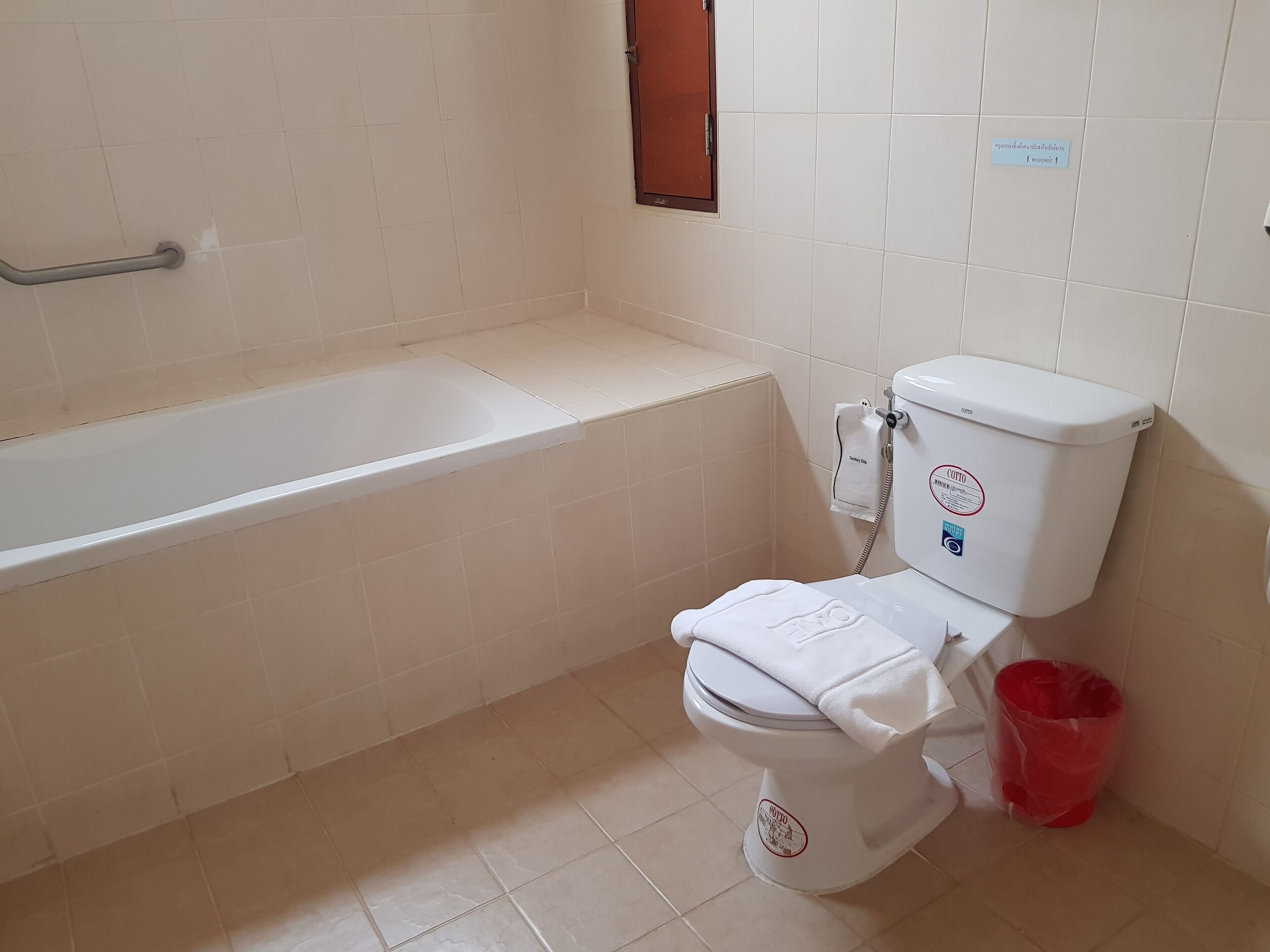 Ein Badezimmer mit einer weißen Badewanne, Toilette und einem roten Mülleimer.