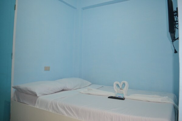 A single bed with white bedding, a remote control, and a swan-shaped towel on a blue wall. - The Beach Anne Boracay (Boracay Island)